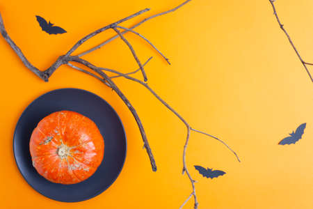 Halloween home paper decorations and pumpkin on black plate on orange background. Trick or treat concept. Copy space.の写真素材