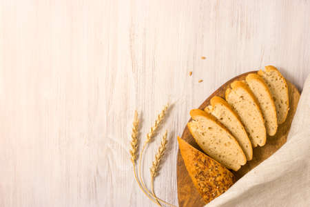 Slices of fresh homemade bread on wooden board with whole grain and seeds. Top view with copy space.