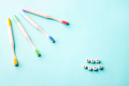 Set of colorful bamboo toothbrushes on blue background. Words eco life on small wooden cubes. Zero...