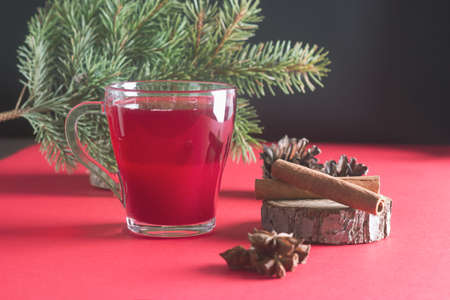 Hot cranberry punch or tea with spices cinnamon sticks and anise stars decorated fur tree brunches. Winter and Christmas evening.の写真素材