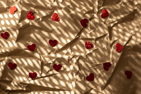 Crumpled craft paper background with little red paper hearts
