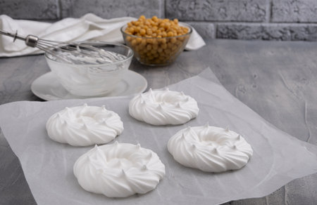 Vegan meringues with whipped aquafaba - chickpea water on baking paper. Bowl with chickpea, whisks nearby. Copy spaceの写真素材