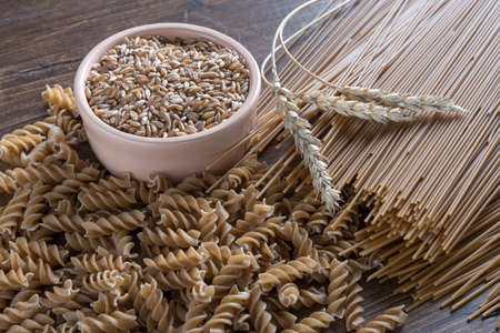 Spelt pasta with seeds and ears on wooden table.の写真素材