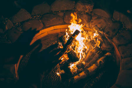 He warms his hands on the fire on a summer evening. He warms his hands on the fire on a summer...