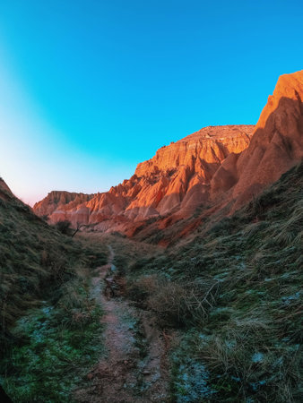 Trail at the foot of the Red Mountains in Turkey. Frosty morning in the Red Valley in Cappadocia. The green grass is covered with frost.の写真素材