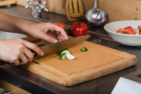Female hands cut a cucumber on the board