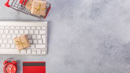 Concept online shopping buying presents. Red credit card, keyborad and christmas presents on grey...