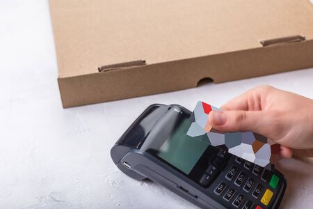 Using payment terminal with contactless credit card, cashless paying for pizza in restaurantの写真素材