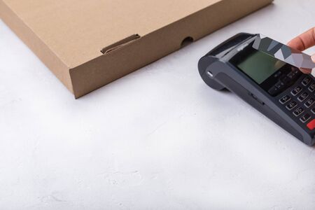 Using payment terminal with contactless credit card, cashless paying for pizza in restaurantの写真素材
