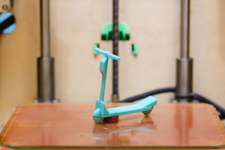 Close-up of a miniature model of a plastic scooter, which is located in a 3D printer after completing a taskの写真素材