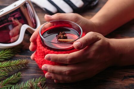 Mulled wine in woman hands cozy home concept ingredients winter sport goggles ski gloves