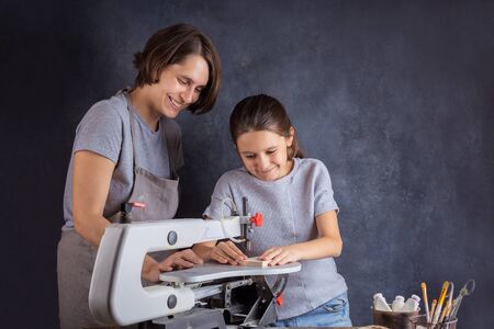 Mom and daughter carve a wooden blank for the Christmas tree decorations for the New Year