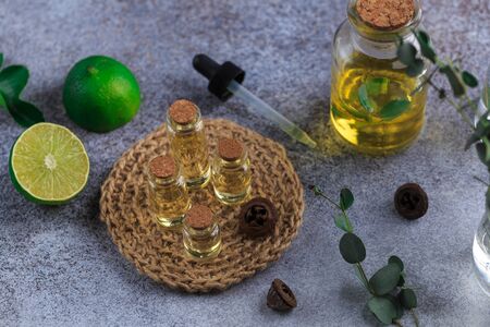 Set of glass bottles with eucalyptus essential oil on grey table leaves in vaseの写真素材