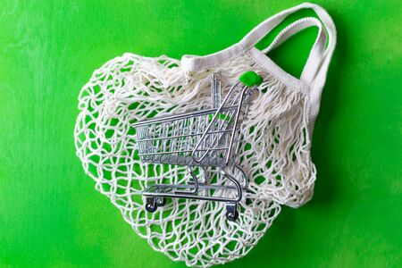 small shopping cart over mesh bag on green no plastic bag concept sustainable living conscious consumptionの写真素材