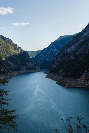 A photo of mountain landscape with a river or lake at the foot of the mountains.の写真素材