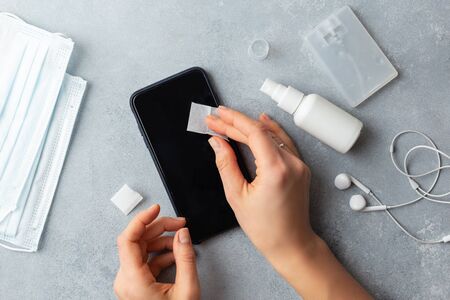 Phone screen disinfecting wipe woman cleaning removing germs with antibacterial wipes for corona virus COVID-19の写真素材