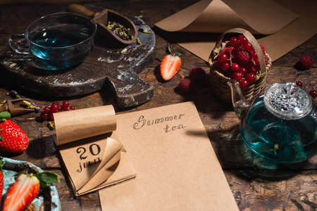 Berry still life. Berries, tea, pen, calendar, notebook on an old brown wooden table, top viewの写真素材
