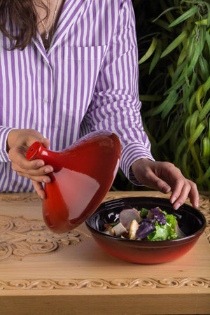Girl opens the lid of the salad bowl with the prepared fresh vegetable saladの写真素材