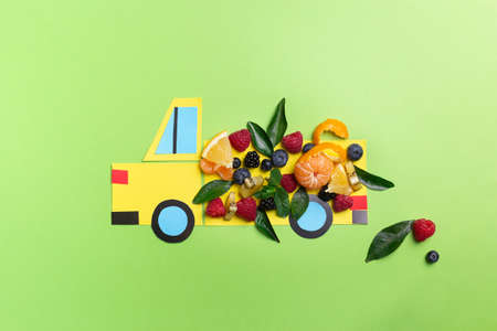 Kids food art concept: paper craft truck with berries and fruits on green concept top view, flat layの写真素材