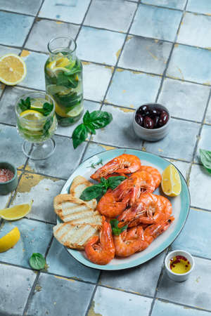 Plate with shrimps on tiles blue table Mediterranean diet lemon and mint lemonadeの写真素材