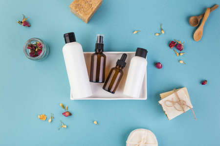 Glass and amber empty bottles. Beauty and cosmetic concept on blue table with flowers around
