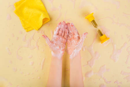Wash hands concept. Washing hands at home. Coronavirus concept. Child hands in foam on yellowの写真素材