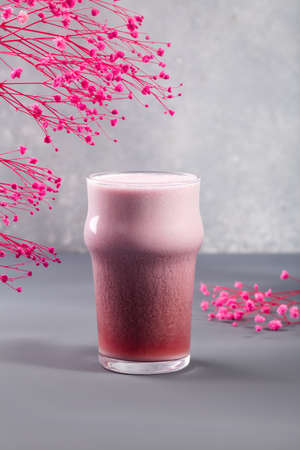 Strawberry latte on grey with flowers behindの写真素材