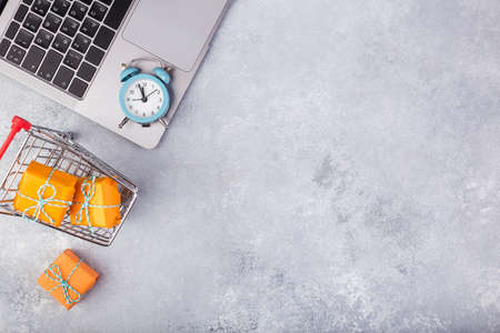 Laptop and orange presents on blue table flat lay. Holiday online shopping concept.の写真素材