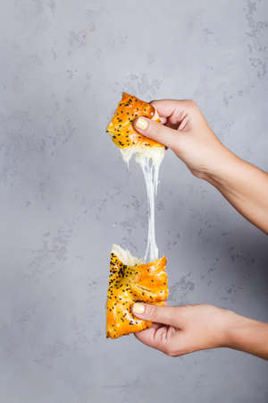 Woman hands takes uzbek national food Tandyr bread Lepeshka with cheese on grey backgroundの写真素材