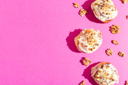 Beautiful fresh cinnamon rolls close-up on pink paper background hard shadow