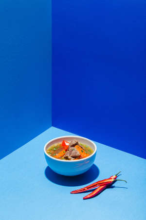 Traditional Asian, Uzbek, Middle East soup with beef or lamb and vegetables. Shorpa, sherpa, chorba on blueの写真素材