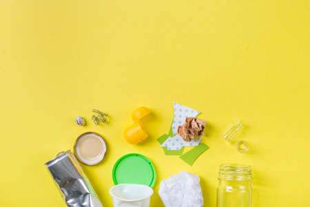 Clean trash to recycle - metal, plastic paper and glass. Recycling concept on yellow.