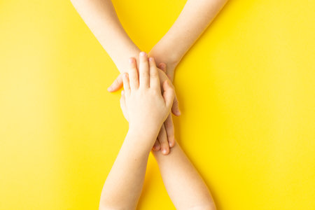 brother and sisters hands holding together on yellow friendship conceptの写真素材