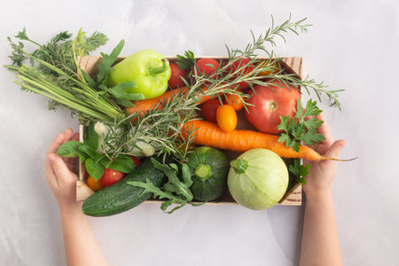 Organic farm vegetables in wooden box, vegetarian food concept child handsの写真素材