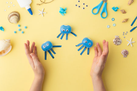 Adorable jellyfish made from plastic blue egg, Kids craft at home or kindergarten. Hands making DIY...