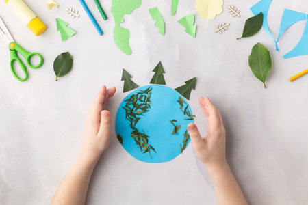 Globe cut from paper and decorated with tree leaves earth day concept kid's paper craft. High quality photoの写真素材