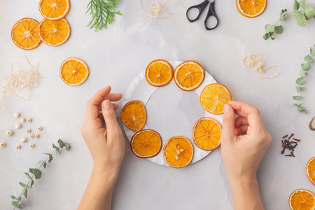 A decorative wreath crafted from dried orange slices, eucalyptus leaves, dried cloves, wooden cuts step by step instruction diy. High quality photoの写真素材