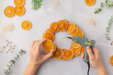 A decorative wreath crafted from dried orange slices, eucalyptus leaves, dried cloves, wooden cuts...