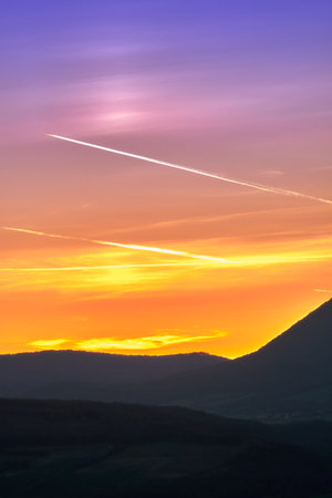 Sunset in the mountains with a trail of a plane and clouds in the sky, closeup photo, colorful...