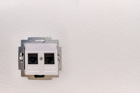 Installing or repairing on-wall internet network socket for a computer, CAT.5E, open during, black contact wall, white plastic, metal frameの写真素材