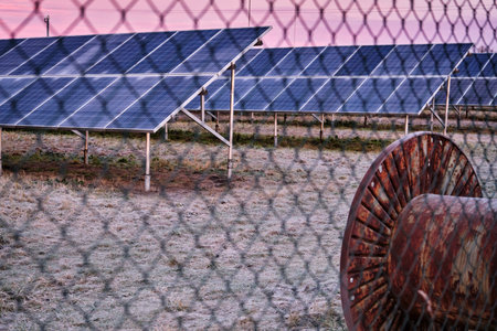 Solar power plant park with panels beyond chain link fence. Subsidized renewable energy source on...