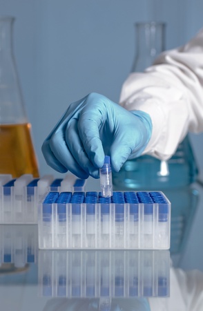 Hand of a lab technician taking a microtube of a rack with a flask in the backgroundの写真素材