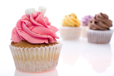 one pink cupcake in the foreground and three more on isolated white backgroundの写真素材