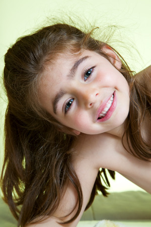 portrait Cute little girl lying in bed ready for bathの写真素材
