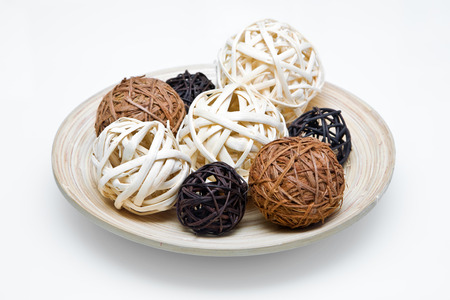 Decorative wooden plate with wicker balls on white backgroundの写真素材