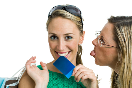 two young shopping, one woman sticking out her tongue and making fun of envy to happy friend   envy on purchasesの写真素材