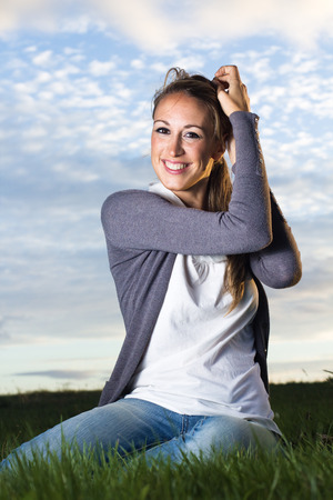 beautiful young woman in field holding her hair in a meeting with friends with blue sky in the backgroundの写真素材