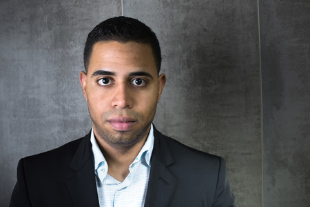 Young latin businessman wearing a suit in front of a gray wall / businessman Youngの写真素材