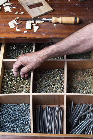 Desk drawer of a cabinetmaker working with several compartments with nuts, screws, nails, bolts / the drawer screwsの写真素材