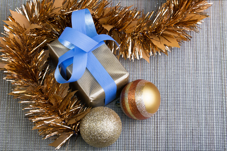 present and christmas balls in gold, red as background gray for copy space / gift and christmas balls in silver tablecloth backgroundの写真素材